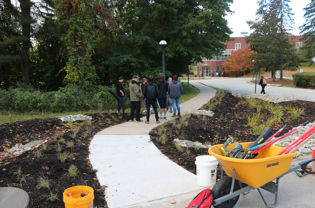 A garden of plantings is being overlooked by students.