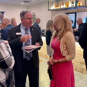 A professional woman and man chat at the event.