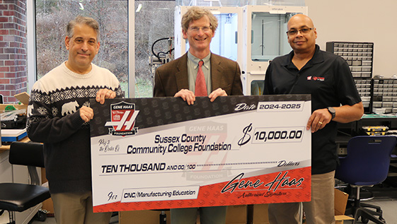 Three business men holding a large check