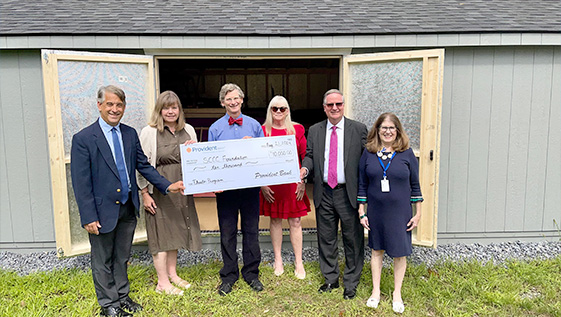 Men and  women stand with a large $10000 check.